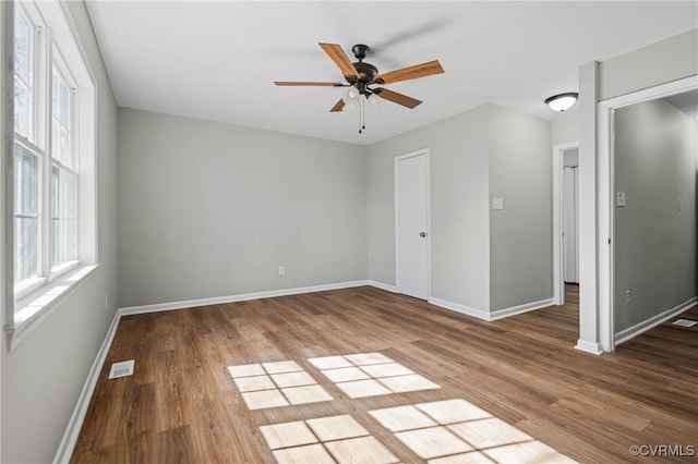 spare room with a ceiling fan, baseboards, visible vents, and wood finished floors