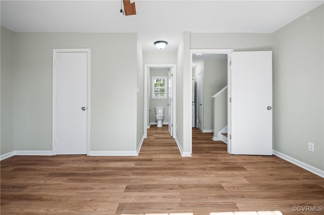 unfurnished bedroom featuring light wood finished floors, baseboards, and a closet