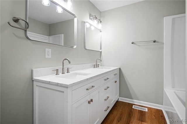 full bathroom with double vanity, wood finished floors, a sink, and visible vents