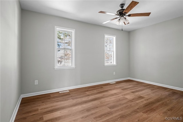 spare room featuring ceiling fan, wood finished floors, visible vents, and baseboards