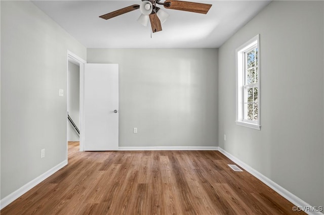 spare room with a ceiling fan, visible vents, light wood-style flooring, and baseboards