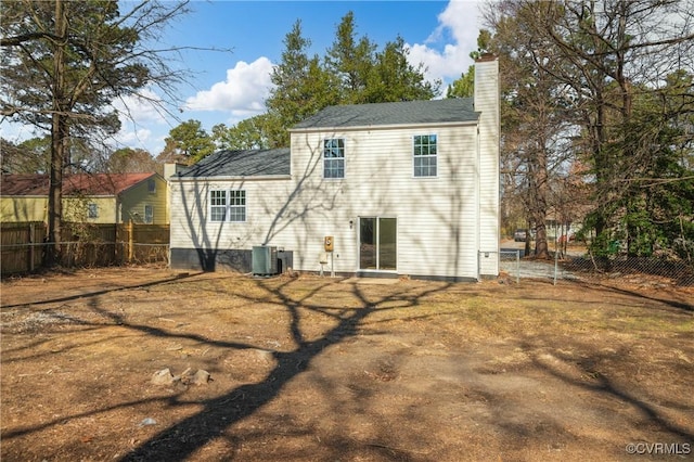 back of property with a chimney, fence, and central AC