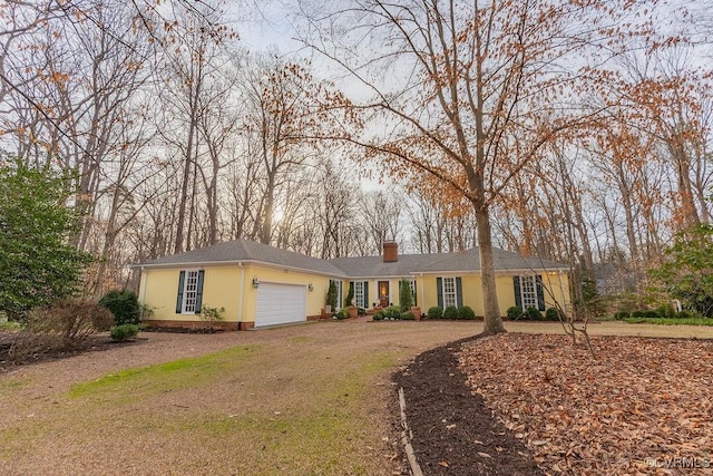 single story home featuring a garage, a chimney, and driveway