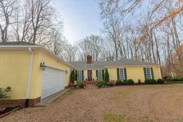 ranch-style home featuring an attached garage, driveway, and a chimney