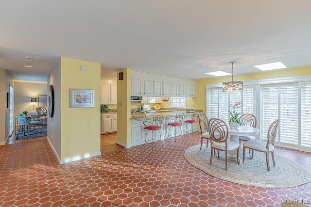 dining area with a wealth of natural light, baseboards, and a skylight