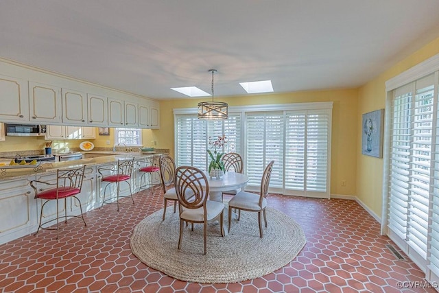 dining room featuring visible vents, plenty of natural light, baseboards, and a skylight