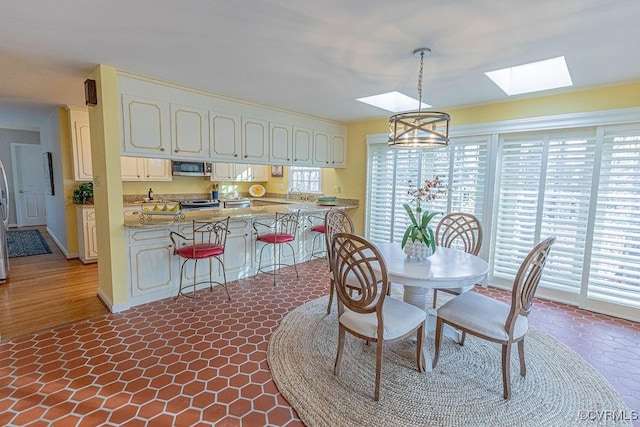 dining area featuring an inviting chandelier and lofted ceiling with skylight