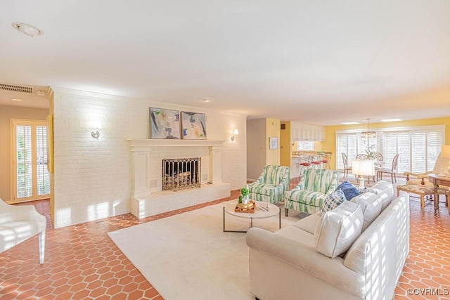 living room with tile patterned floors, visible vents, a fireplace with raised hearth, and a healthy amount of sunlight