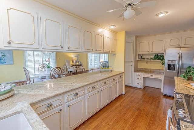 kitchen with light wood-type flooring, appliances with stainless steel finishes, a healthy amount of sunlight, and built in study area