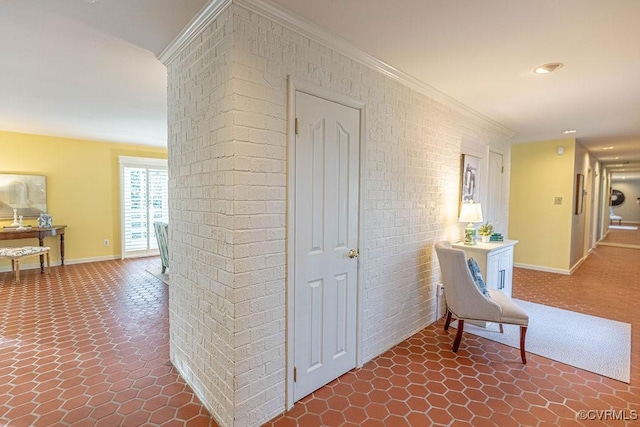 hall with baseboards, dark tile patterned flooring, brick wall, and crown molding