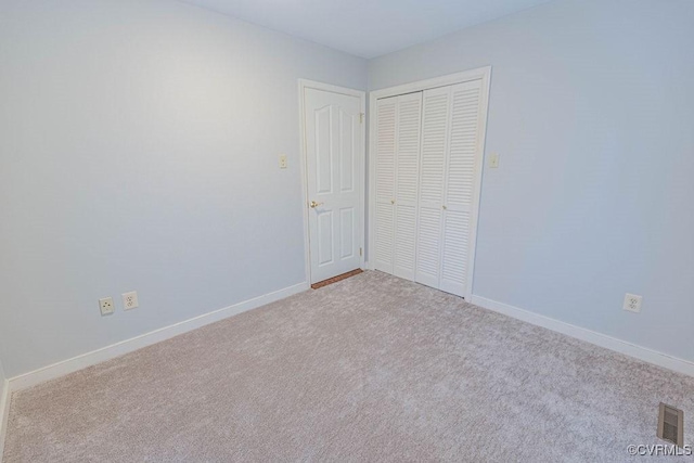 unfurnished bedroom with a closet, visible vents, carpet flooring, and baseboards