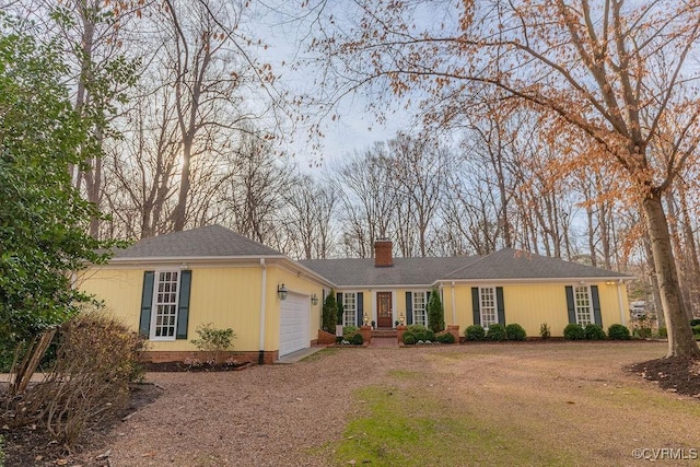 ranch-style house with driveway, an attached garage, roof with shingles, and a chimney