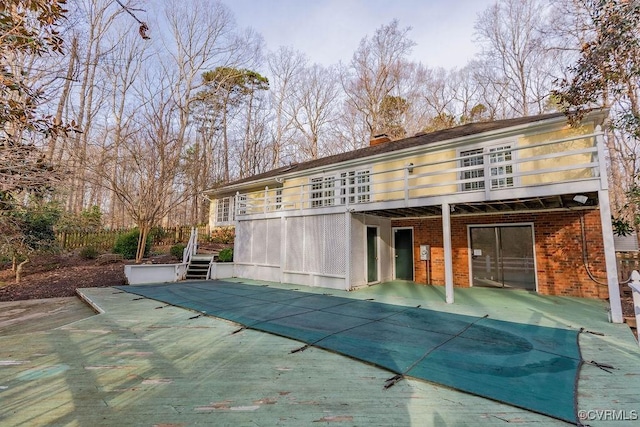 back of house with a patio, stairway, a wooden deck, brick siding, and a chimney