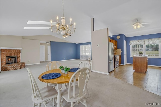 dining area featuring a ceiling fan, a healthy amount of sunlight, a fireplace, and vaulted ceiling