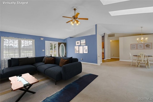 living area with carpet, baseboards, visible vents, lofted ceiling with skylight, and ceiling fan with notable chandelier