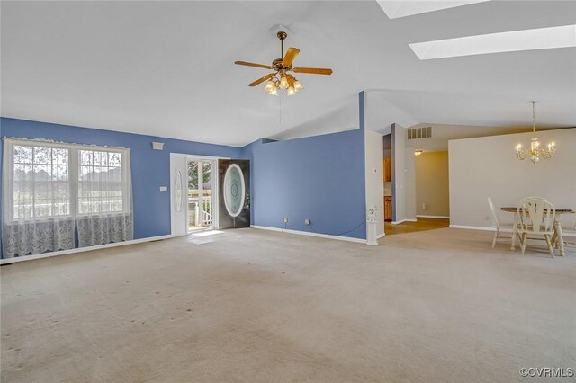 unfurnished living room with lofted ceiling with skylight, ceiling fan with notable chandelier, visible vents, and carpet floors