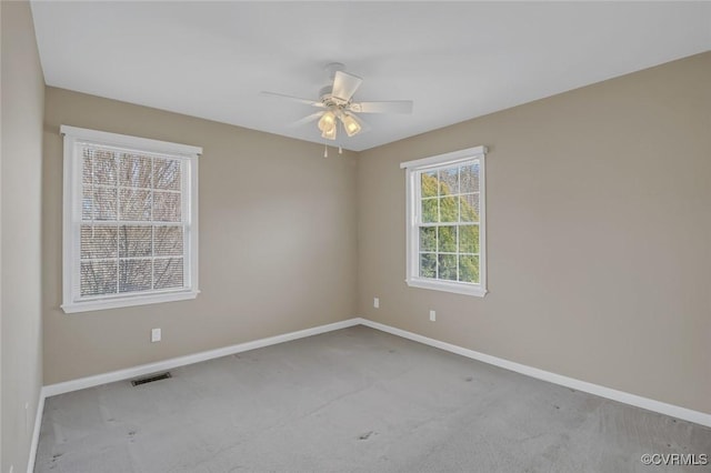 carpeted spare room featuring visible vents, baseboards, and a ceiling fan