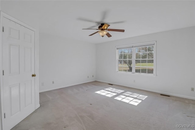 carpeted empty room with baseboards, visible vents, and ceiling fan