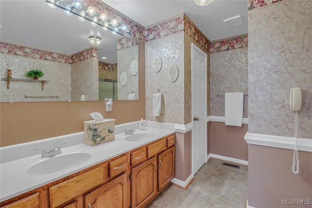 bathroom with a sink, visible vents, double vanity, and wallpapered walls