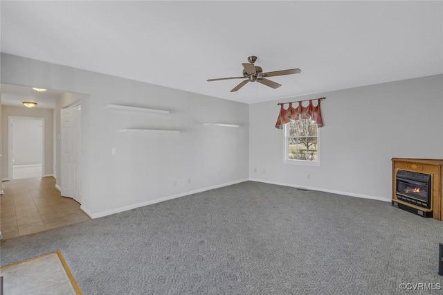 unfurnished living room featuring a glass covered fireplace, ceiling fan, baseboards, and carpet