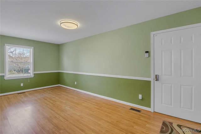 spare room with visible vents, baseboards, and wood finished floors