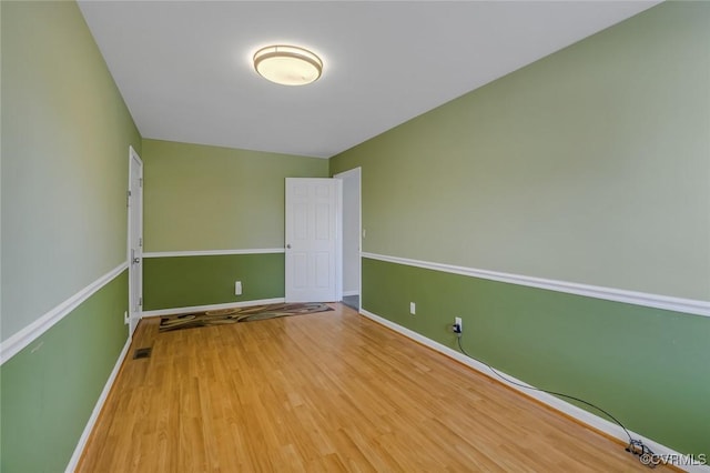 empty room with visible vents, baseboards, and wood finished floors