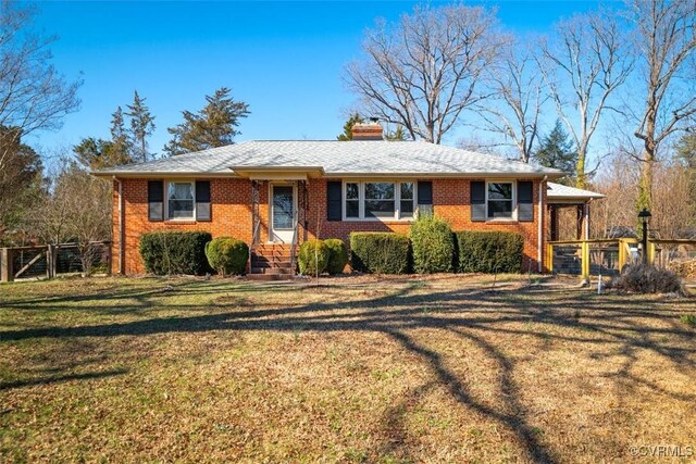 ranch-style home with brick siding, a chimney, a front yard, and fence