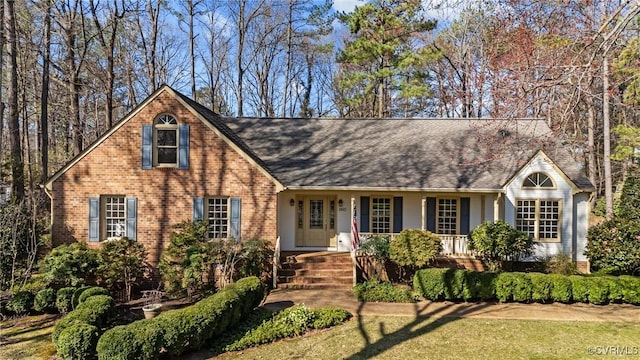 view of front of home with brick siding, a porch, and a front yard