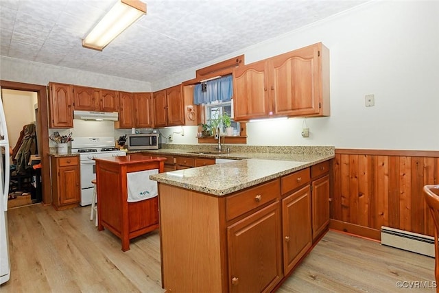 kitchen with white range with gas stovetop, a wainscoted wall, stainless steel microwave, baseboard heating, and under cabinet range hood