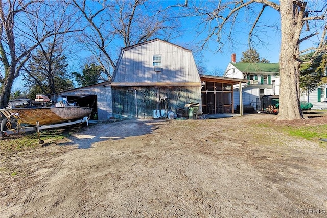 back of property featuring a barn, an outbuilding, a sunroom, and a gambrel roof