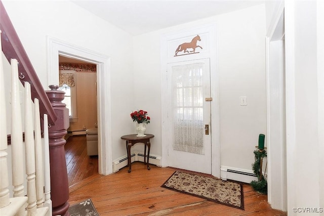 foyer entrance featuring a baseboard heating unit, a baseboard radiator, stairway, and hardwood / wood-style floors