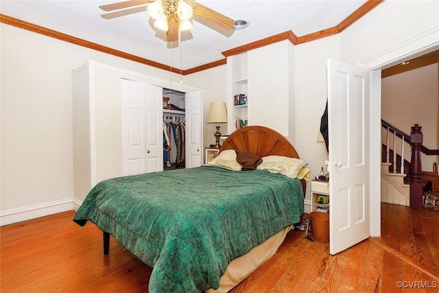 bedroom with ceiling fan, wood finished floors, baseboards, a closet, and crown molding