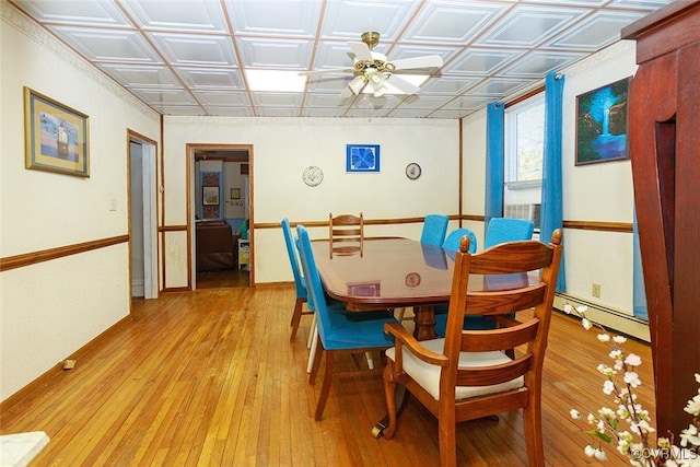 dining space featuring an ornate ceiling, light wood-type flooring, baseboard heating, and a ceiling fan