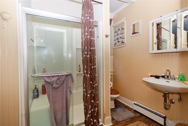 bathroom with toilet, baseboard heating, ornamental molding, a sink, and wood finished floors