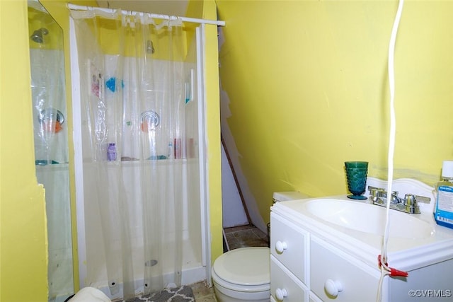 bathroom with toilet, a stall shower, and vanity