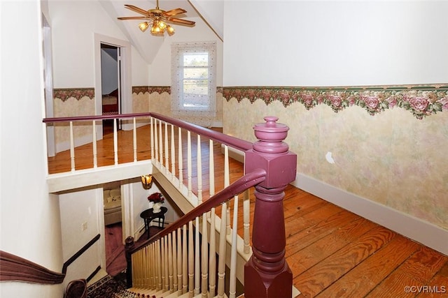 stairway with lofted ceiling, a wainscoted wall, ceiling fan, and wood finished floors