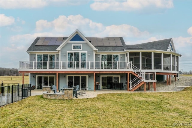 back of property featuring a sunroom, stairs, roof mounted solar panels, and a patio