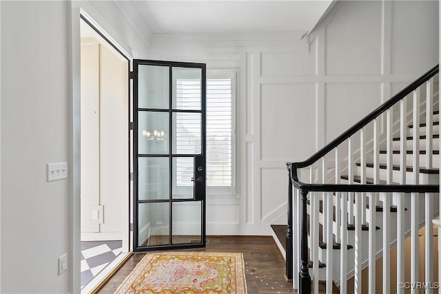 entrance foyer featuring dark wood-style floors, a decorative wall, and stairway