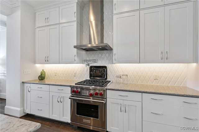 kitchen with white cabinetry, luxury range, light stone countertops, wall chimney exhaust hood, and tasteful backsplash