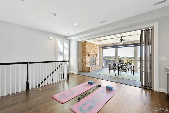 workout area with a healthy amount of sunlight, a fireplace, visible vents, and wood finished floors