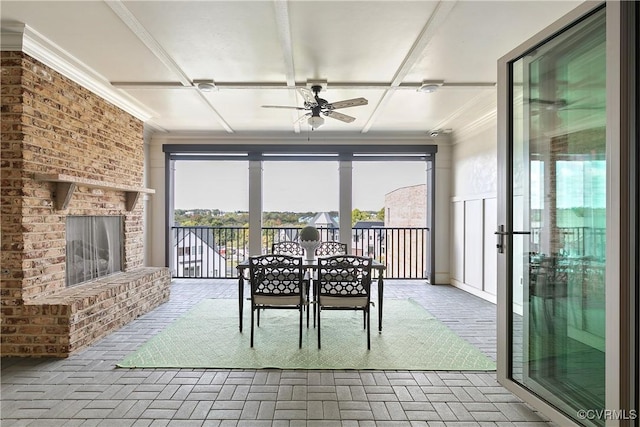 unfurnished dining area with brick floor, a brick fireplace, ceiling fan, and ornamental molding