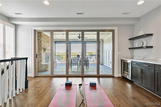 workout area featuring dark wood-style floors, wine cooler, and visible vents