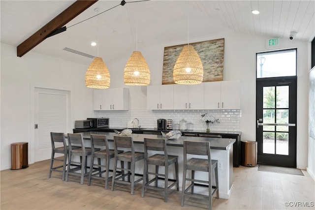 kitchen with dark countertops, pendant lighting, white cabinets, and a kitchen breakfast bar