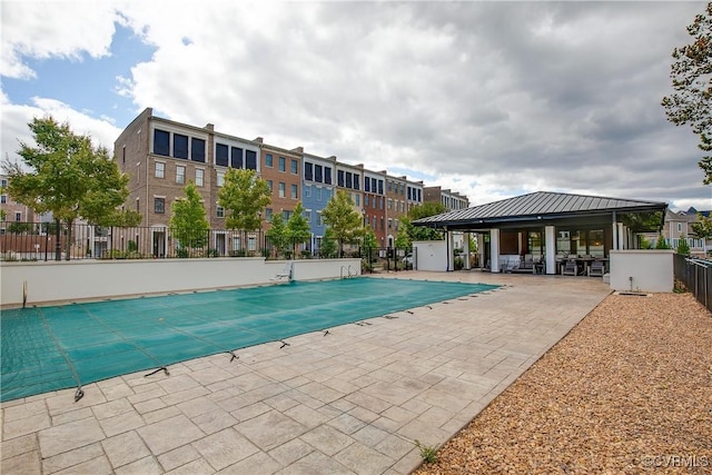 pool with a patio area, fence, and a gazebo