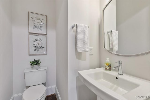 bathroom featuring baseboards, a sink, and toilet