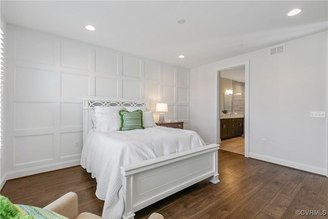 bedroom featuring recessed lighting, dark wood finished floors, visible vents, and a decorative wall