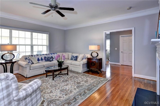 living room featuring a fireplace, ornamental molding, ceiling fan, wood finished floors, and baseboards