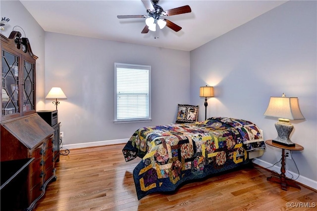 bedroom featuring baseboards, ceiling fan, and light wood-style floors