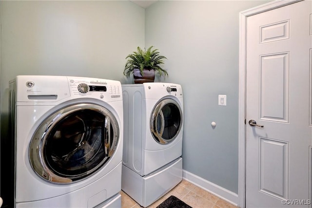 laundry room featuring laundry area, washer and clothes dryer, baseboards, and light tile patterned floors