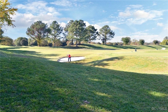 view of community with golf course view and a lawn